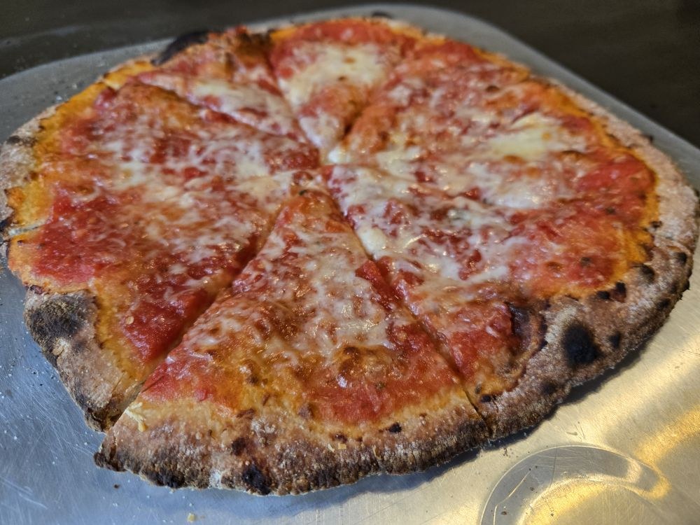A close-up of a sliced pizza showing its blistered crust and melted cheese